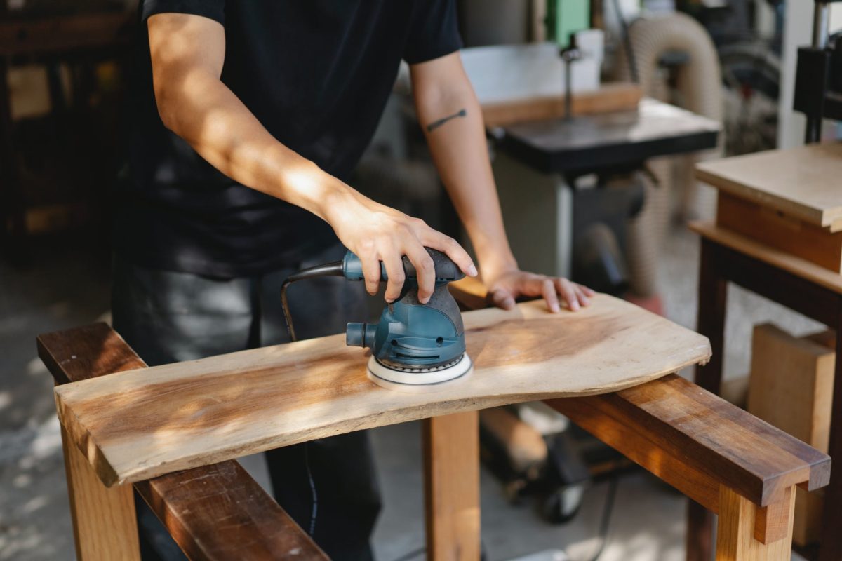 craftsman polishing wooden board with grinding instrument